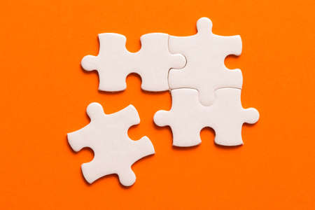 Four white details of puzzle on orange background.の写真素材