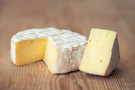 A soft ripened Camembert cheese on dark wooden board.の写真素材