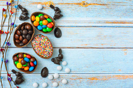 Flat lay composition with Chocolate Easter eggs, rabbit and sweets on blue wooden background. Top view. With copy space.の写真素材