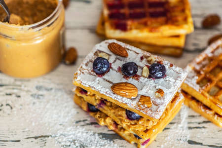 Waffles with peanut butter and blueberry berries on light wooden table. Close up, Selective focus.の写真素材