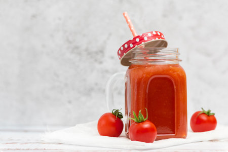 Fresh tomato juice in jar and cherry tomatoes on light background. With copy space.の写真素材