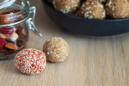 Energy bites from dates, cashew, raisins, cranberry and almond on light wooden table.
