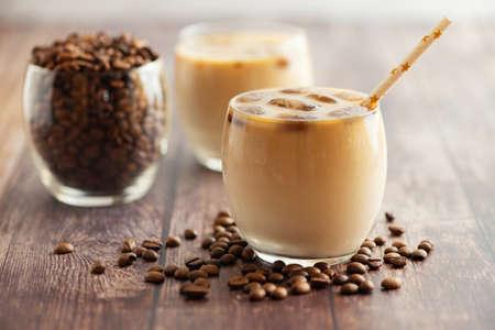 Milk coffee cocktail in glasses with frozen coffee cubes on wooden table. Side view.の写真素材