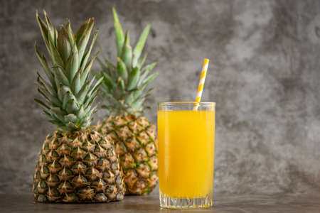 glass of pineapple juice with fresh fruits on gray bacground.の写真素材