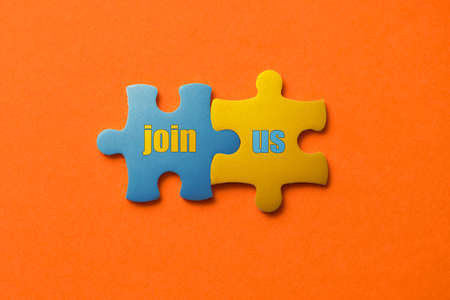Two colored details of puzzle with text join us on orange background, Yellow and Blue, close up ..の写真素材