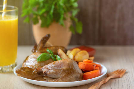 Roasted chicken, potatoes and vegetables in white plate on wooden background.の写真素材