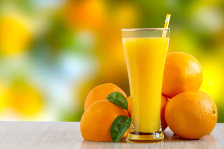 Tall glass of tasty freshly squeezed orange juice standing on an outdoor table with a fresh oranges.の写真素材
