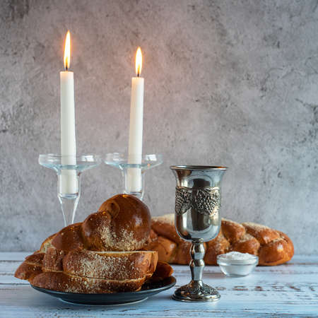 Shabbat Shalom - challah bread, shabbat wine and candles on wooden table.