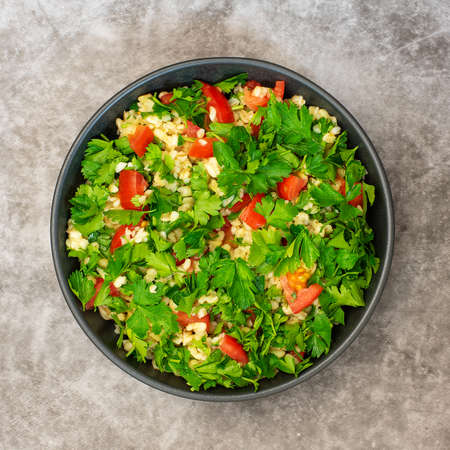 Tabbouleh salad with bulgur, parsley, spring onion and tomato on gray background. Top view.の写真素材