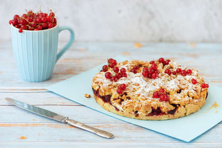 Tasty homemade pie and fresh red currants in cup on light blue background.の写真素材