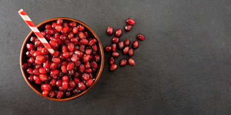 Pomegranate seeds in a bowl on a dark background.の写真素材