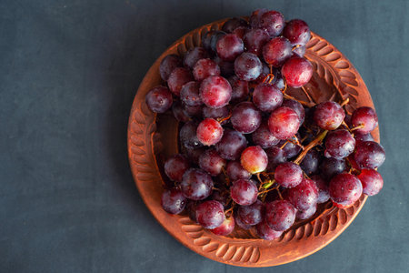 grape on brown plate on dark background with copy space.の写真素材
