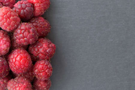 Ripe sweet raspberries on dark background. Close up, top view, with copy spaceの写真素材