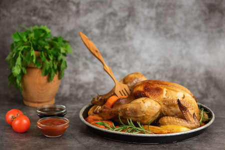 Roasted chicken, potatoes and vegetables in plate on gray background. Side view.の写真素材