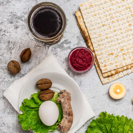 Jewish holiday Passover background with wine, matza and seder plate on gray background. Top view....