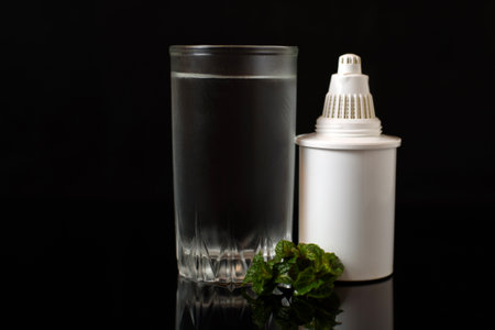 Glass of fresh water and Water Filter cartridge on a black background.の写真素材