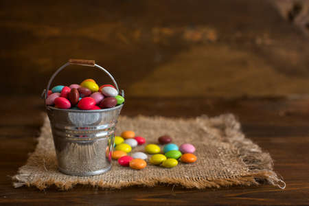 color candy dragee in a decorative bucket on a napkin from burlap.