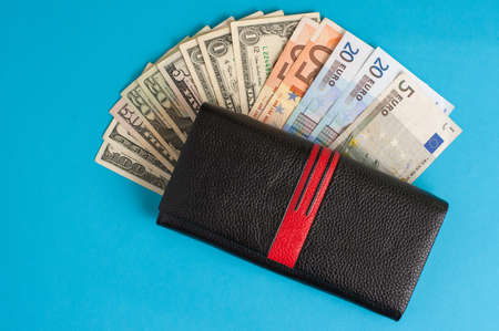 black leather wallet on banknotes on a blue background.の写真素材