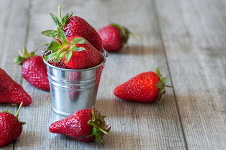 fresh strawberry in small bucket on a gray wooden background.の写真素材