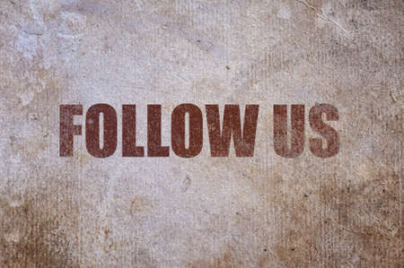 Brown text follow us on old paper background.の写真素材