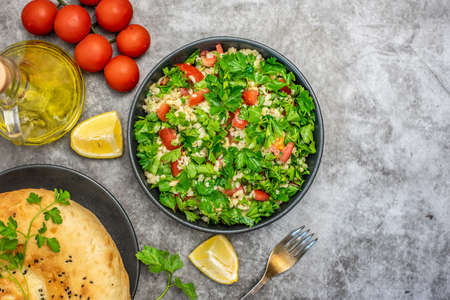 Tabbouleh salad with bulgur, parsley, spring onion and tomato in bowl on gray background. Top view. WIth copy space.の写真素材