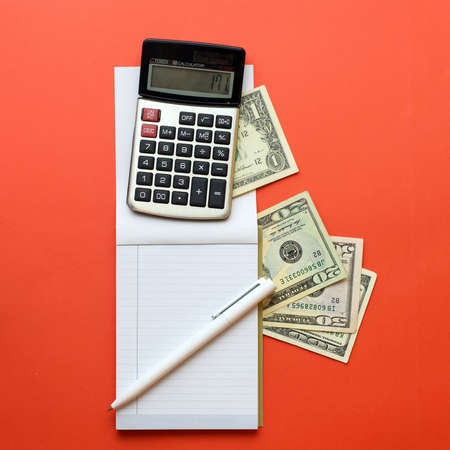 Notepad with calculator, money and pen on red background. Business and education concept. Top view.の写真素材