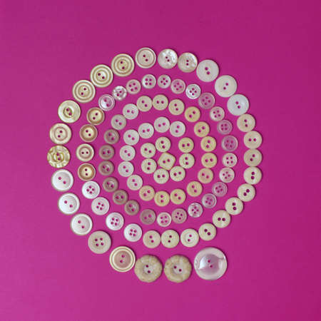 Spiral from beige vintage buttons on purple background. Top view.の写真素材