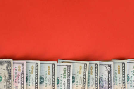 Dollar cash. Many dollar banknotes on red background with copy space.の写真素材