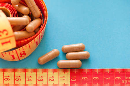 measure tape with medicaments pills on light blue background. With copy space.の写真素材