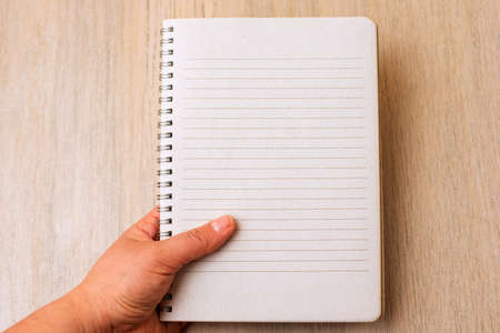 Blank empty notebook in hand on a light background.の写真素材