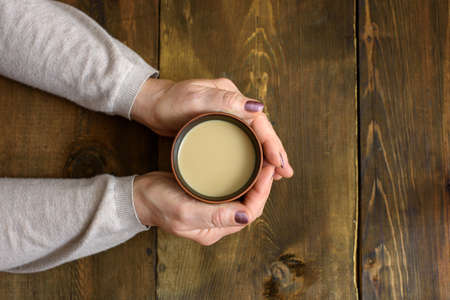 cup of coffee and hands on wooden background. Top view.の写真素材