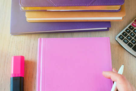 pink notebook with calculator, marker and hand with a pen. Top view.の写真素材