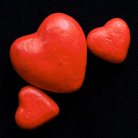 Three red heart of different sizes on dark background.の写真素材