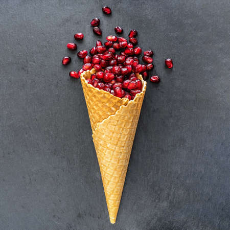 Pomegranate seeds in waffle cone on dark background.の写真素材