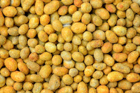 Fried peanut grains with a coating of savory spices. Peanuts in batter macro detail background.の写真素材