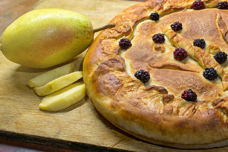Homemade Apple pie. Cake with pieces of apples and a pear on a wooden board. Close Up.の写真素材