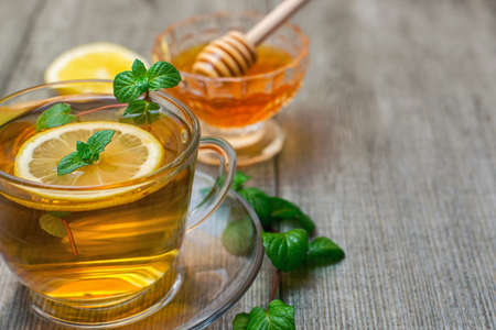 Glass tea Cup with lemon, honey and mint on gray wooden background.の写真素材