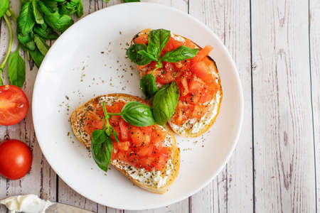 Traditional toasted Italian tomato bruschetta with spice and basil on light wooden background. Top view vith copy space.の写真素材