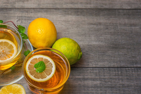 Two Glass tea Cup's with lemon, lime and mint on gray wooden background.の写真素材