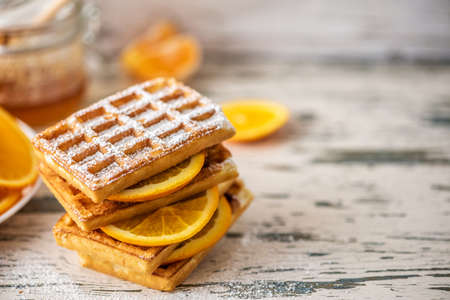 Tasty waffles with sliced oranges on light wooden table. Close up, Selective focus.の写真素材