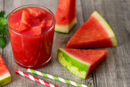 Watermelon smoothie in jars with fresh watermelon slices on gray wooden background.の写真素材