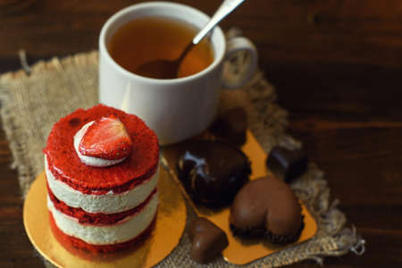 cake with strawberries, biscuits and a Cup of tea on a wooden table.