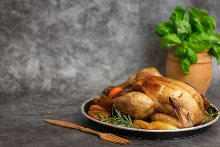 Roasted chicken, potatoes and vegetables in plate on gray background. Side view. With copy space.の写真素材