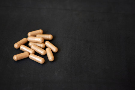 Scattered medicine capsules on dark background. Top view with copy space.