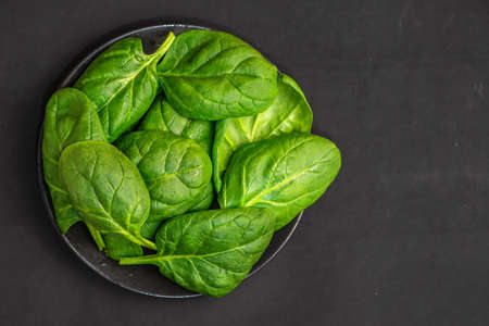Fresh spinach leaves in bowl on dark background. Top view. With Copy Space.の写真素材