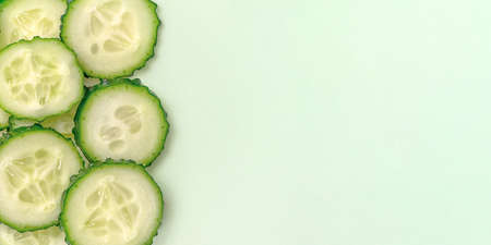 Sliced fresh cucumber on light green background. Close up, top view. With copy space.の写真素材