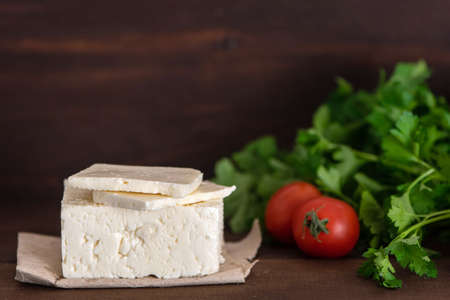 Large piece of feta cheese on dark wooden table. Selective focus.の写真素材