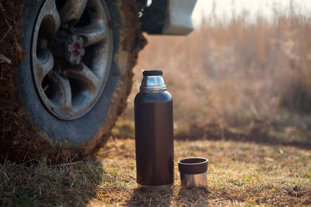 Flask on the background the wheels of the SUV. Rest and relax.の写真素材