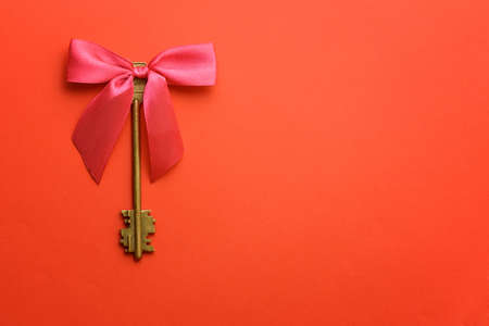 Vintage keys with pink bow over red background.の写真素材