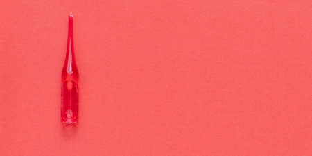 Medical red ampoule on red background. With copy space.